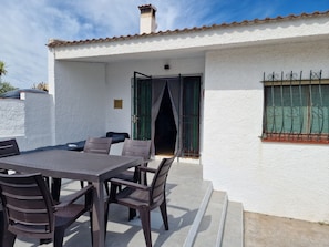 A patio with a table and chairs, a door, and a window with metal bars. - "Maritim"@MARISOL: 50m to the beach, private pool, A/C, WiFi, dog beach (Riumar)