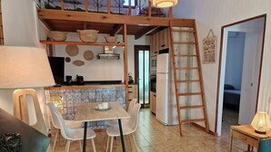 Una cucina con tavolo e sedie di legno, un frigorifero e una scala.
