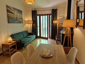A living room with a sofa, dining table, chairs, and a painting on the wall. - "Maritim"@MARISOL: 50m to the beach, private pool, A/C, WiFi, dog beach (Riumar)