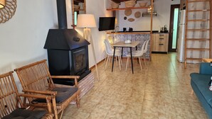 Un accogliente soggiorno con camino, poltrone in vimini, un tavolo da pranzo e un angolo cottura.