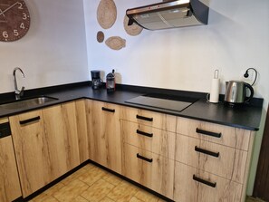 A kitchen with wooden cabinets, a sink, a coffee maker, a kettle, and a wall clock. - "Maritim"@MARISOL: 50m to the beach, private pool, A/C, WiFi, dog beach (Riumar)