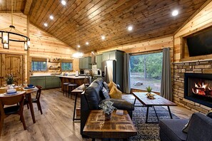 Ein Holzblockhaus-Interieur mit Essbereich, Küche, Wohnzimmer und Kamin.