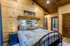 Ein Schlafzimmer einer Holzhütte mit einem Bett, Nachttischen und einem Bild an der Wand.