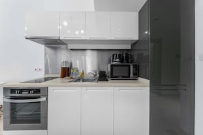 Eine moderne Küche mit Edelstahlgeräten, weißen Schränken und einem schwarzen Kühlschrank.