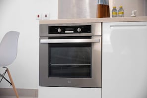 Eine Küche mit Einbauofen, einem weißen Schrank und einer Arbeitsplatte mit zwei Flaschen und einem Dosierspender.