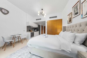 Ein modernes Schlafzimmer mit einem großen Bett, einem Esstisch und einer Küchenzeile im Hintergrund.