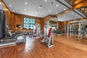 Ein Fitnessstudio mit Cardiogeräten, Krafttrainingsgeräten und einem großen Spiegel.