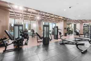 Ein modernes Fitnessstudio mit unterschiedlichen Trainingsgeräten, großen Fenstern und einem gefliesten Boden.