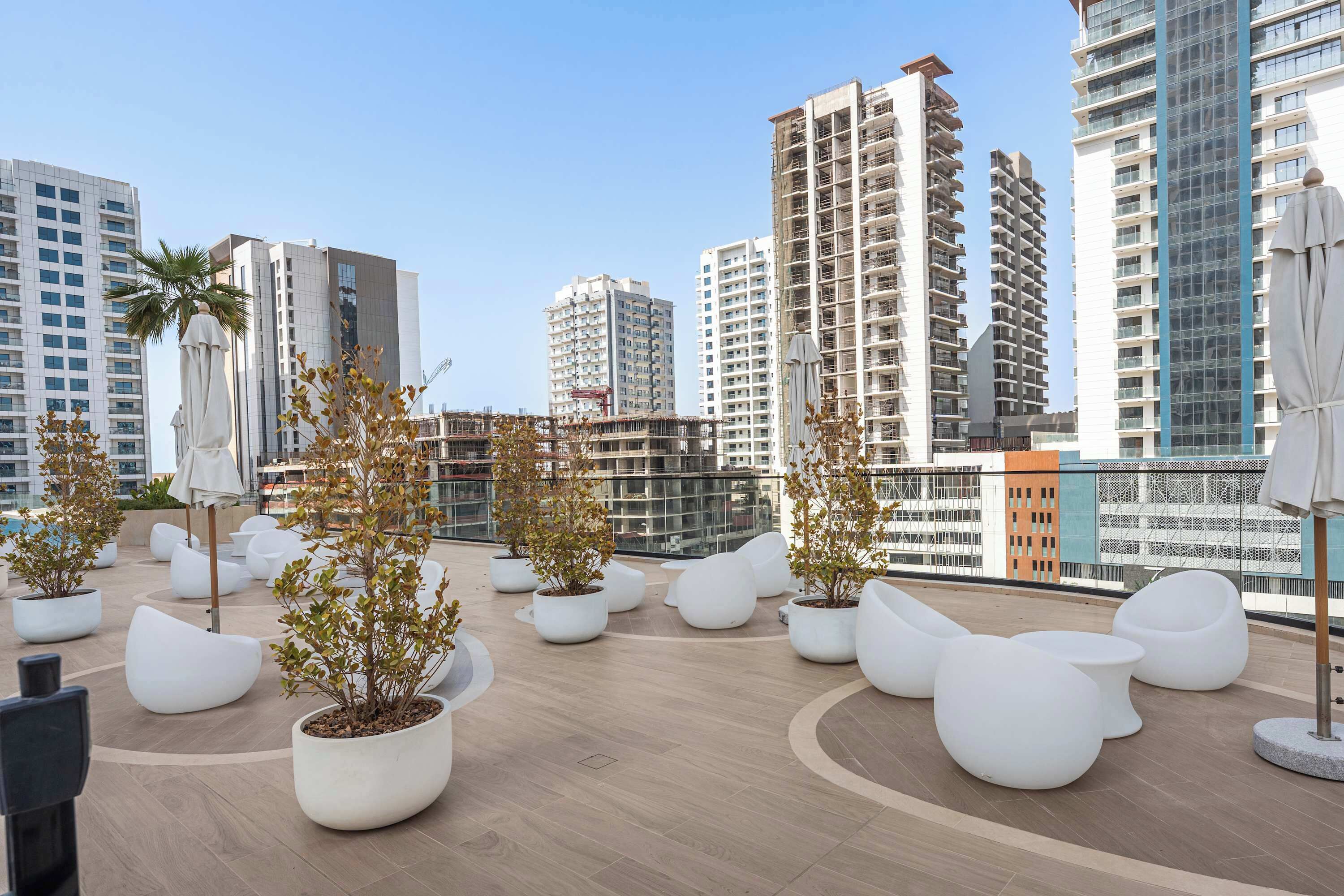 Terraza en la azotea con mobiliario moderno, plantas en macetas y vistas al horizonte de la ciudad.
