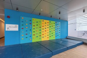 Eine Wand mit einer Kletterwand und einem Schild, das an Kinder richtet sich.