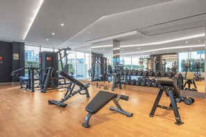 Un gimnasio moderno con diversos equipos de ejercicio, amplias ventanas y suelo de madera.