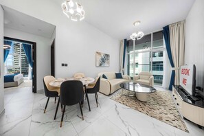 Una sala de estar moderna con comedor, un sofá, un televisor y un amplio ventanal con cortinas.