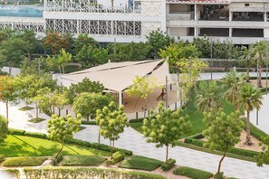 Un edificio moderno con fachada geométrica, rodeado de vegetación cuidada y un camino despejado.