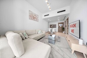 Ein modernes Wohnzimmer mit einer Couch, einem Couchtisch und einem Fernseher auf einem Schrank.
