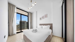Una camera da letto moderna con un letto grande, vista sulla città e una porta scorrevole in vetro.