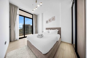 Ein modernes Schlafzimmer mit einem großen Bett, Blick auf die Stadt und einer Schiebetür.
