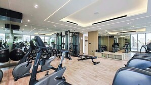 Una palestra moderna con macchinari cardio, attrezzature per l'allenamento con i pesi e uno specchio a parete.