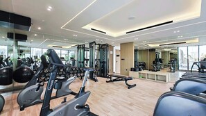 Ein modernes Fitnessstudio mit Laufbändern, Kraftgeräten und einer Spiegelwand.