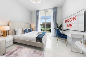 Ein modernes Hotelzimmer mit einem großen Bett, einem Schreibtisch, einem Fernseher und Blick ins Freie.
