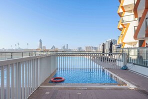 Ein Pool auf dem Dach mit freiem Blick auf die Skyline der Stadt, einer Glasuhr und einem Rettungsring.