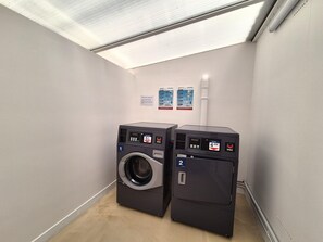 A laundry room with two washing machines, a ceiling light, and informational posters on the wall. - Chalet With Swimming Pool 500m From the Beach (Saint-Pair-sur-Mer)