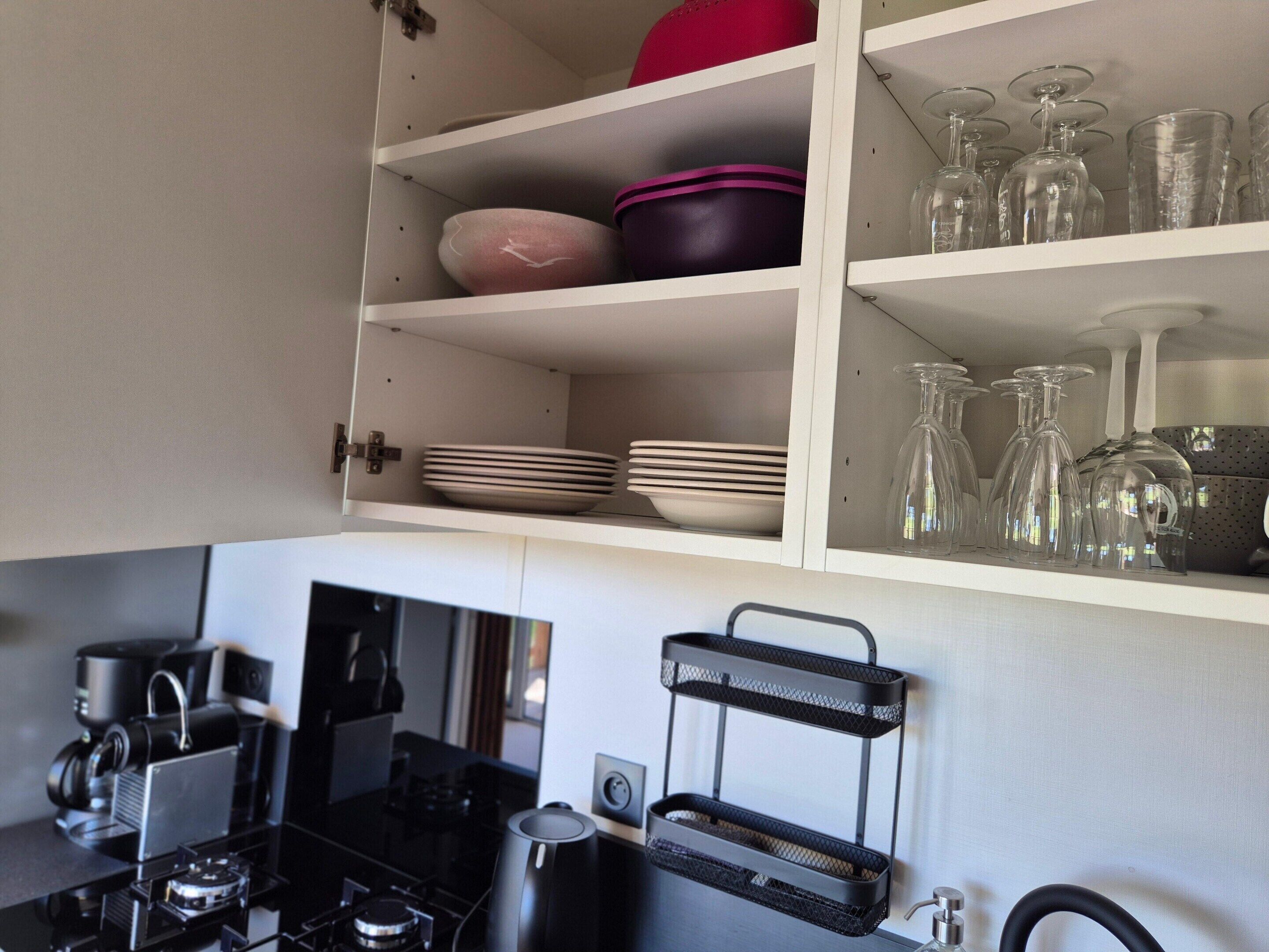 A kitchen with a stove, coffee maker, and a black hanging rack.