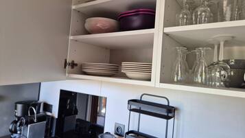 A kitchen with a stove, coffee maker, and a black hanging rack.