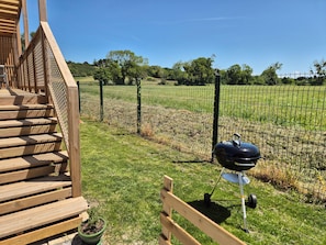 A wooden staircase leading to a deck, a barbecue grill, and a fenced field with trees. - Chalet With Swimming Pool 500m From the Beach (Saint-Pair-sur-Mer)