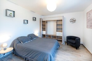A bedroom with a bed, bedside lamps, a chair, a wardrobe, and a small table. - Gîte Rural Gure Lana: Holiday Home with Mountain View, Wi-Fi, and Air Conditioning (Larressore)