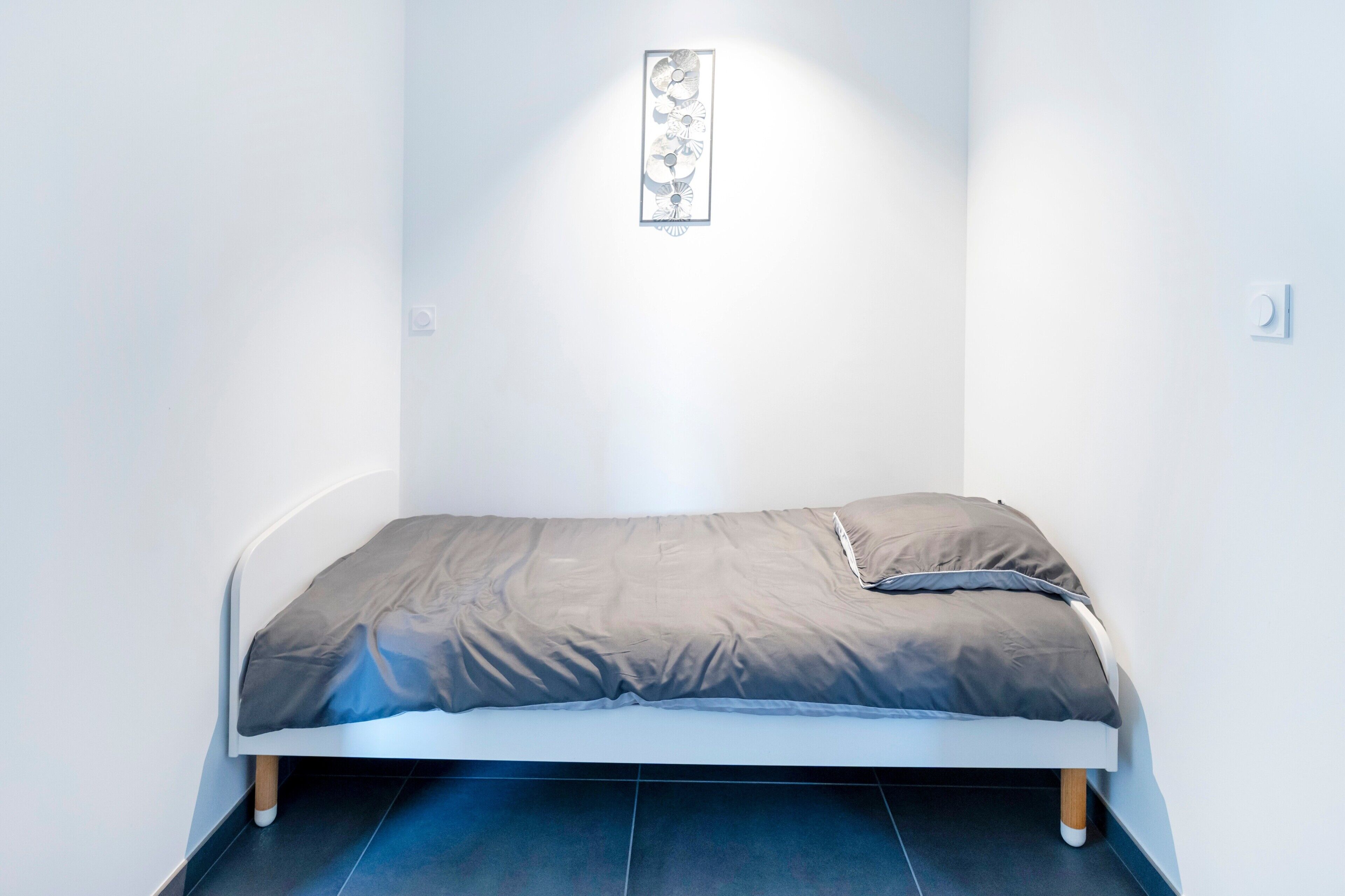 Una habitación pequeña con cama individual y diseño moderno y sencillo.