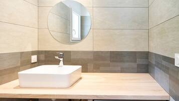 A modern bathroom with a rectangular sink, a round mirror, and a Bosch Maxx 7 water heater.