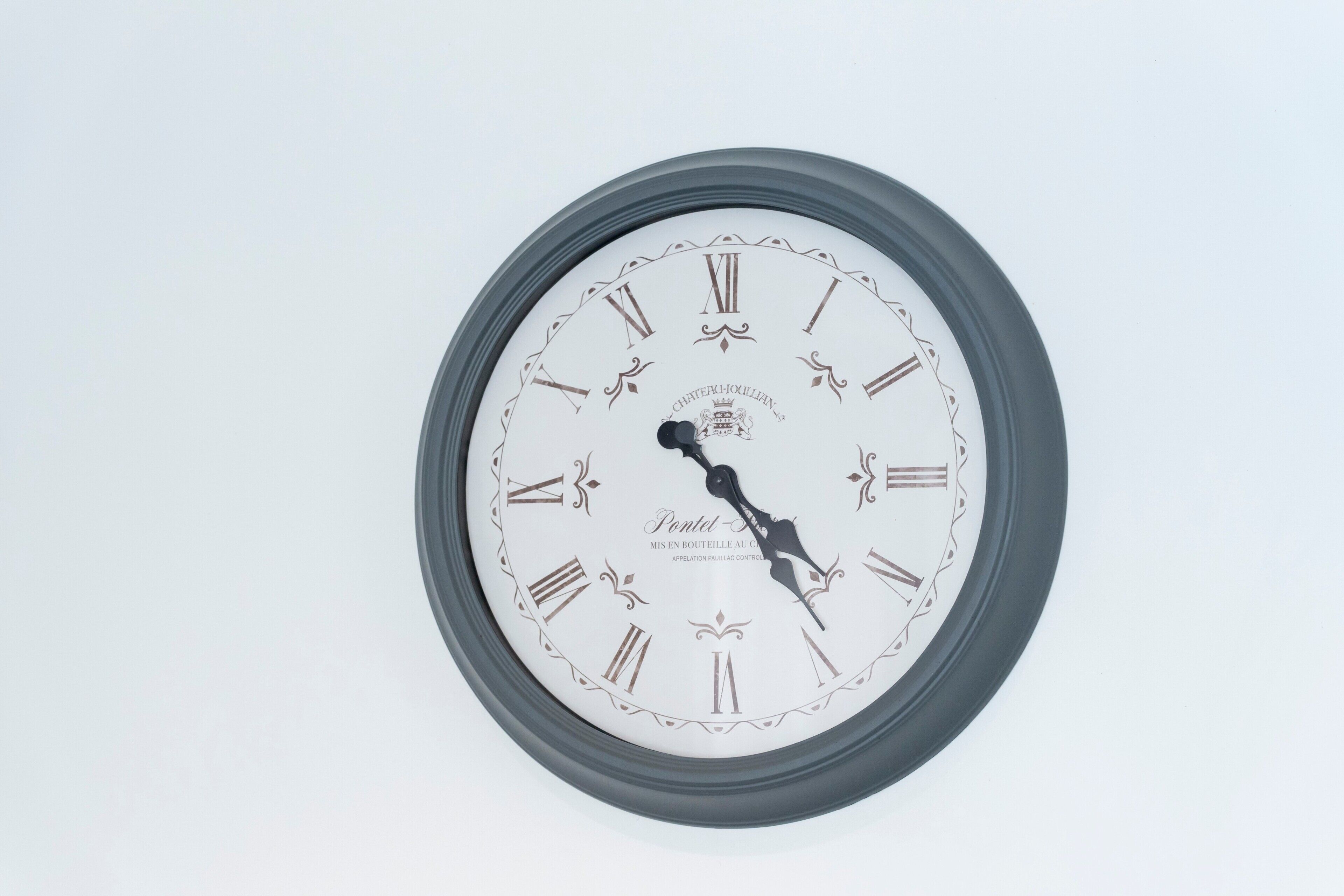 A wall-mounted clock with Roman numerals and decorative elements.