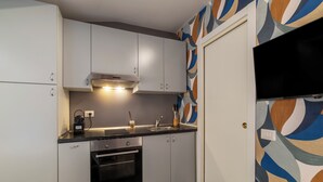 A kitchen with white cabinets, a stove, an oven, a sink, and a microwave. - Via del Corso Quiet Design Studio | Elevator (Roma)