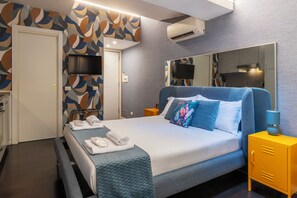 Ein modernes Hotelzimmer mit einem großen Bett, einem Nachttisch, einem Spiegel, einem Fernseher und einem Badezimmer.
