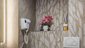 A bathroom with a hairdryer, a vase with flowers, a reed diffuser, and a thermostat. - Via del Corso Quiet Design Studio | Elevator (Roma)