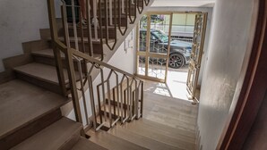 Una escalera de madera con barandillas de metal que conduce a una puerta de cristal.