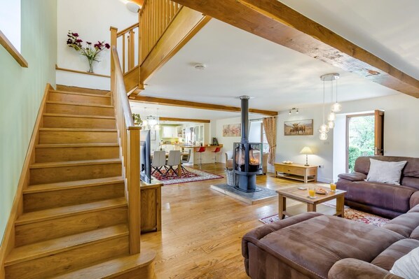 A spacious living area with a wooden staircase, a central fireplace, and a cozy seating arrangement. - 5 Bed in Garth (oc-c44957) (Treflys)