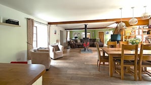 A spacious living room with a wooden dining table, a fireplace, and a view into the adjacent dining area. - 5 Bed in Garth (oc-c44957) (Treflys)
