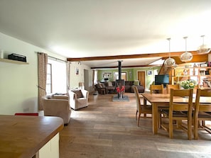 Ein geräumiges Wohnzimmer mit einem Holzesstisch, einem Kamin und Blick in den angrenzenden Essbereich.