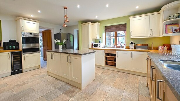 A modern kitchen with a central island, built-in appliances, and a view to the outside. - 5 Bed in Garth (oc-c44957) (Treflys)