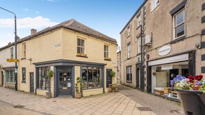 Une rue où se trouve une boutique appelée « Rosemary & Thyme » et un bâtiment portant l’enseigne « Serendipity Interiors ».