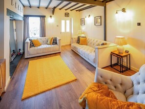 Ein Wohnzimmer mit zwei Sofas, einem gelben Teppich und einem kleinen Tisch mit einer Lampe.