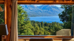 Una habitación con un ventanal grande con vistas a un lago y montañas.