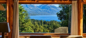 A room with a large window overlooking a lake and mountains.