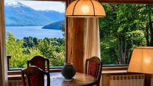 Una habitación con una mesa, sillas, un florero y vistas a un lago y montañas.