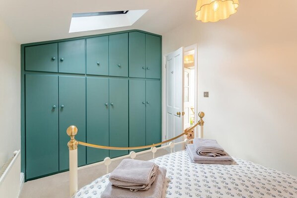 A bedroom with a bed, a wardrobe, a skylight, and a hanging light fixture.