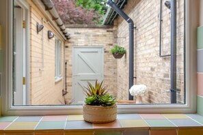 A window view of a brick building with a door, a potted plant on the windowsill, and a hanging plant. - 1 Bed in Great Ayton (oc-h44914) (Great Ayton)