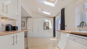 Una cocina moderna con armarios blancos, lavavajillas y encimera de madera.