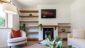 Una sala de estar con chimenea, televisor montado encima y un sofá.