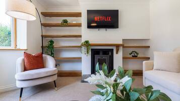 A living room with a fireplace, a TV mounted above it, and a sofa.